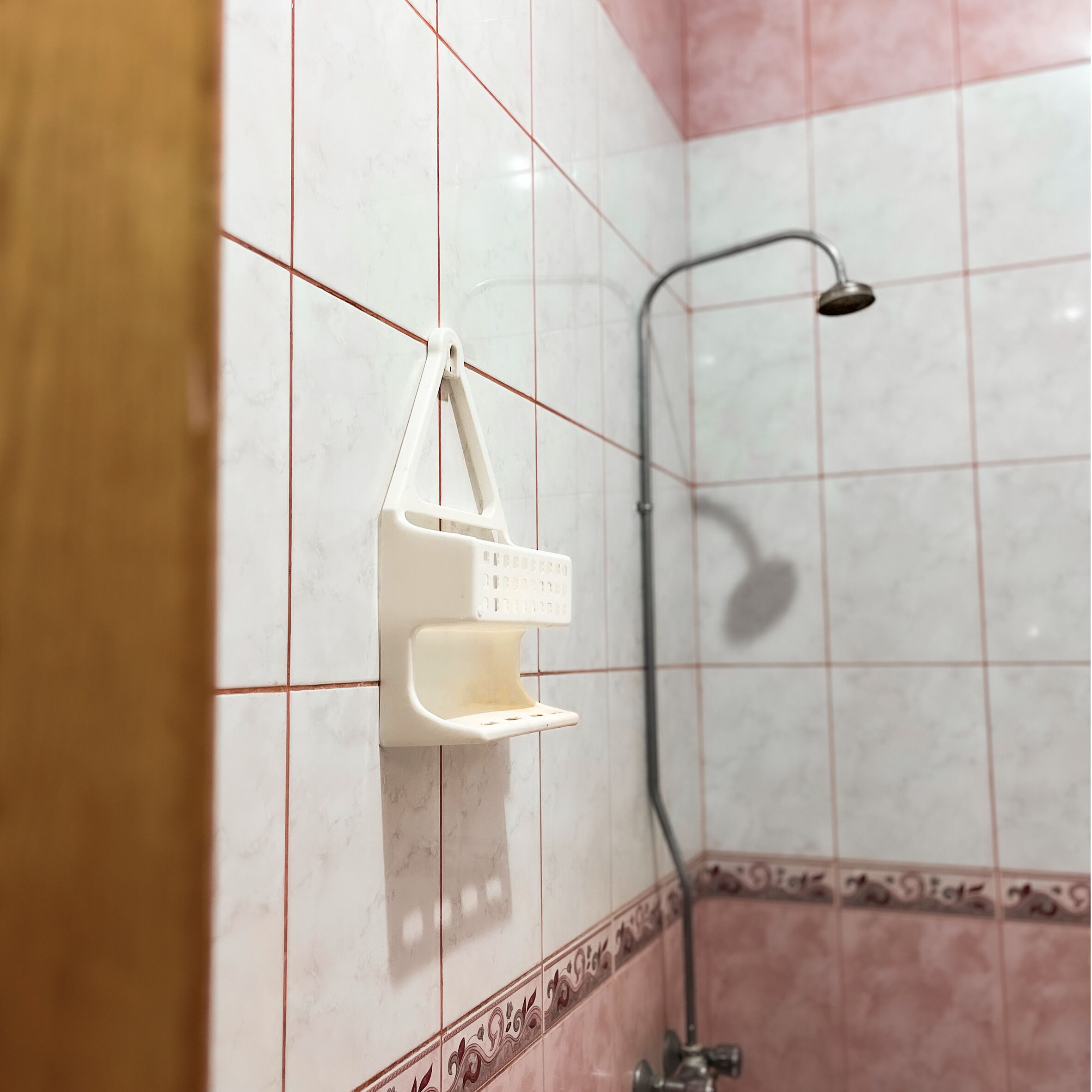 Uma casa de banho com chuveiro, um porta-toalhas branco e uma moldura de azulejos decorativa.