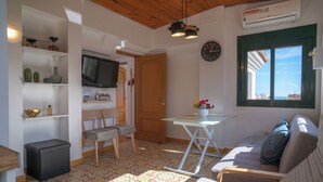 Een knus woongedeelte met een kitchenette, een bank, een eettafel en een televisie.