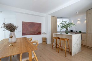 Eine moderne Küche mit Holzausstattung, einer Marmorinsel und Barhocker.