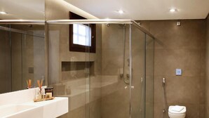 Une salle de bain moderne avec une douche à parois de verre, un lavabo blanc avec un miroir et des toilettes.