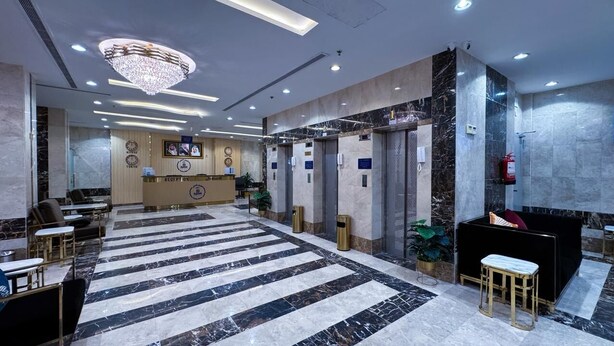Een hotel receptie met een receptiebalie, zithoek en een grote kroonluchter.