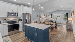 A modern kitchen with white cabinets, stainless steel appliances, and a blue island.