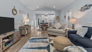 A spacious living room with a TV, sofa, and dining area.