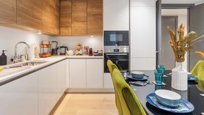 Een moderne keuken met houten kastjes, een ingebouwde oven en een eethoek met een tafel gedekt voor twee personen.