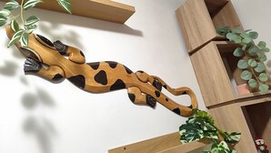 A wooden sculpture of a giraffe with a plant branch, placed on a white wall. - Albi House Vomero modern apartment in the heart of Naples. (Napoli)