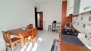 A compact kitchen with a dining area, a small bar stool, and a stove. - Albi House Vomero modern apartment in the heart of Naples. (Napoli)