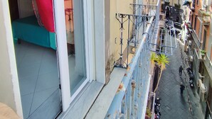A narrow urban street with a building featuring a balcony with a metal railing and a red curtain. - Albi House Vomero modern apartment in the heart of Naples. (Napoli)