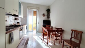 A modern kitchen with a dining area, a TV, and a balcony. - Albi House Vomero modern apartment in the heart of Naples. (Napoli)