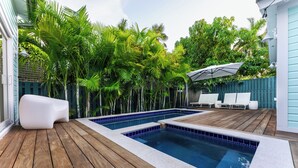 Piscina com deck de madeira e uma espreguiçadeira branca.