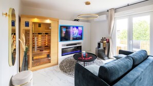 Ein modernes Wohnzimmer mit Flachbildfernseher, Kamin, Sofa und großem Fenster.