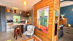 Une cuisine moderne avec un mur en bois, un coin bar et un espace détente avec une chaise et des tabourets.