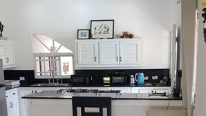A modern kitchen with white cabinets, a marble floor, and a central island with two chairs. - Villa Tropical Deluxe No. 10, near the beach, Cabarete (Cabarete)