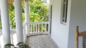 A covered outdoor area with a patterned floor, a wooden bench, and a potted plant. - Villa Tropical Deluxe No. 10, near the beach, Cabarete (Cabarete)