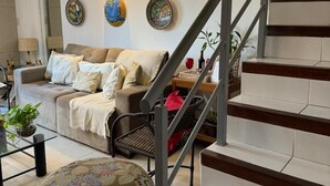 Una sala de estar moderna con una escalera, un sofá, una mesa de centro y decoración en la pared.