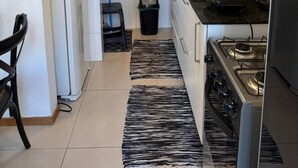 Una cocina compacta con gabinetes blancos, estufa a gas, refrigerador y encimera negra.