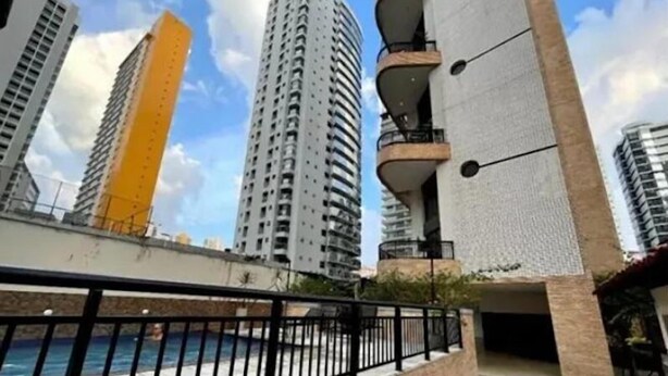 Un edificio de gran altura con balcones, piscina y pared de ladrillo.