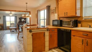 A kitchen with wooden cabinets, a microwave, and a dishwasher. - Oct Festival HQ 2 blocks from Main St + Fire Pit! (Fredericksburg)