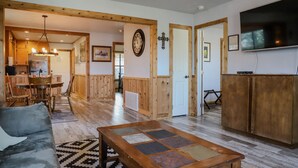 A spacious living room with a sofa, a coffee table, and a dining area with wooden furniture. - Oct Festival HQ 2 blocks from Main St + Fire Pit! (Fredericksburg)
