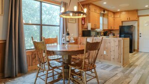 A wooden dining table with chairs, a chandelier, and a kitchen with wooden cabinets and appliances. - Oct Festival HQ 2 blocks from Main St + Fire Pit! (Fredericksburg)