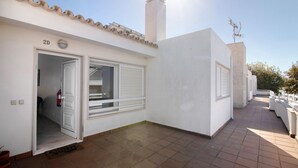 Un edificio blanco con techo de tejas, una puerta y una ventana con contraventanas.