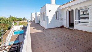 Un edificio residencial con piscina, balcón y vistas despejadas del entorno verde.