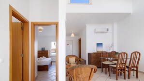 Una habitación con una cama, una mesa de comedor con sillas y una pequeña cocina.