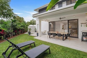 Ein modernes Haus mit Terrasse, Essbereich und Garten.
