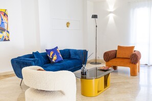 Un soggiorno moderno con un divano blu, una poltrona bianca e una poltrona arancione.