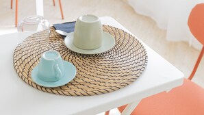 A table with a woven placemat, a white plate, a blue cup, and a clear glass. - Villa Vetrano – Spacious Apartment in Nola (Cimitile)
