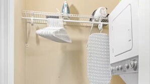 Un espace dédié à la lessive, comprenant un lave-linge, un étendoir et une étagère avec des produits de lessive.