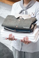 Une personne tenant une pile de chemises soigneusement pliées.