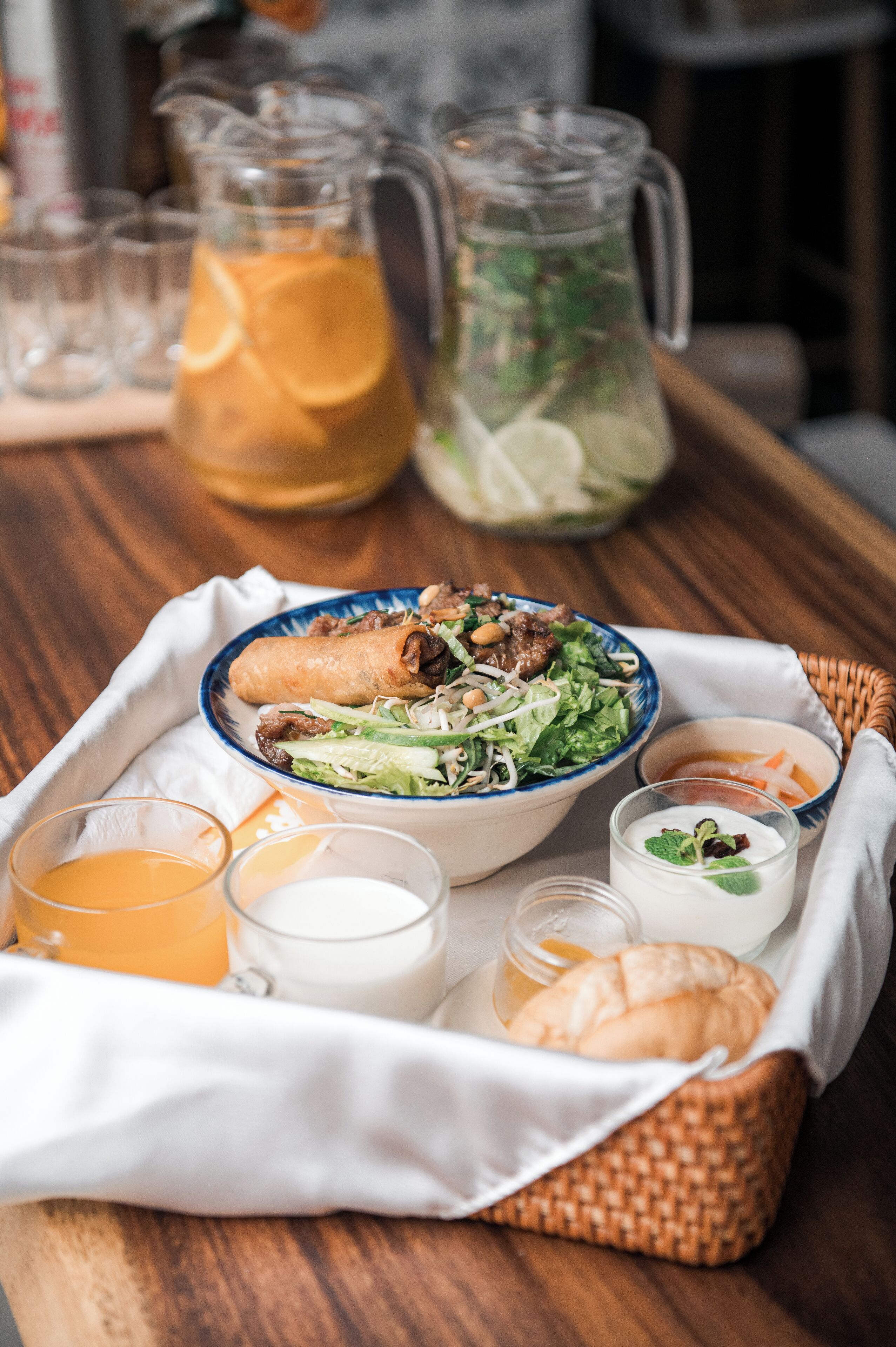 Un plateau contenant une salade, une soupe et des boissons, posé sur une table en bois.