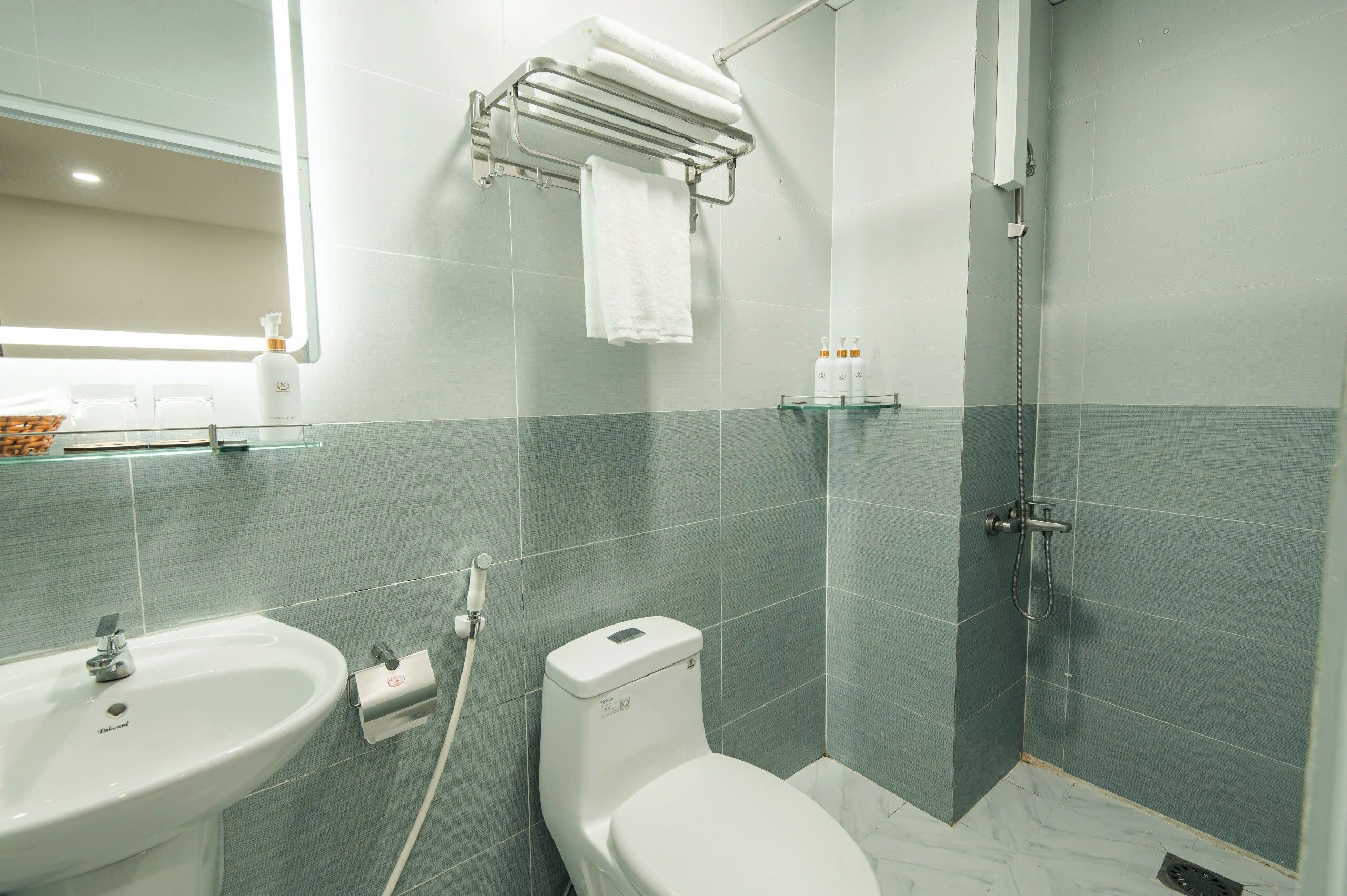 Et moderne badeværelse med vask, toilet og brusebad.