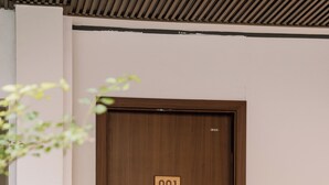 Una porta in legno con una targa che riporta il numero '001' e una maniglia moderna.