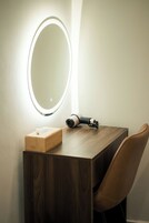 A wooden vanity with a mirror, a hairdryer, and a tissue box.