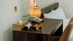 Un comodino in legno con un portatovaglioli di carta, un telefono, un paio di forbici e una lampada.
