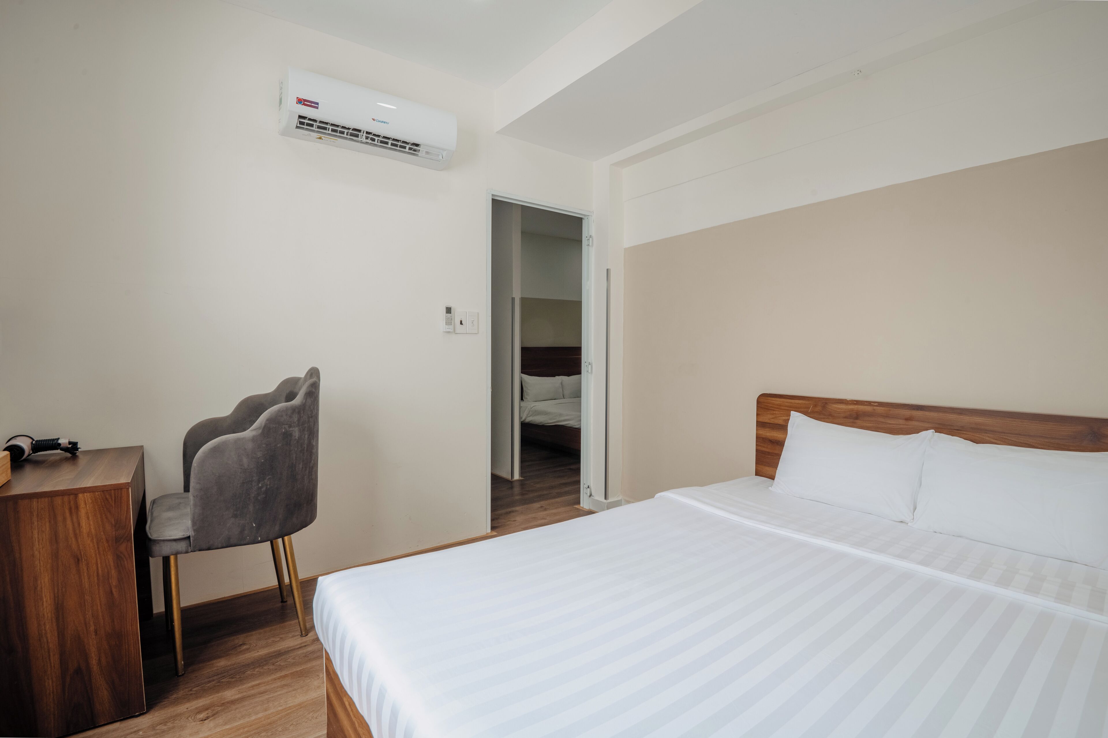 Quarto de hotel com cama, cadeira, escrivaninha e ar condicionado.
