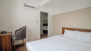 Quarto de hotel com cama, cadeira, escrivaninha e ar condicionado.