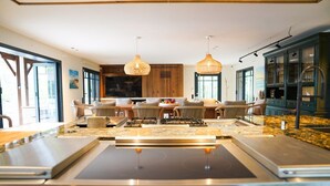 Una cocina moderna con una isla central, armarios de madera e iluminación colgante.