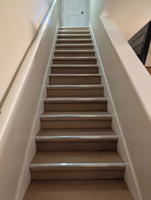 Un escalier avec des marches de couleur beige et des murs blancs.