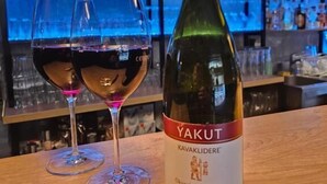 A bottle of Yakut Kavakliderle wine and two glasses on a wooden bar counter. - Gasthaus Sofram (Frastanz)