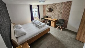 A modern hotel room with a bed, a desk, a chair, and a TV. - Gasthaus Sofram (Frastanz)