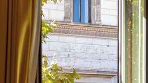 A window with a view of a building's facade, including a balcony with a railing and a window with shutters. - Romantic Stay near Santa Maria
Maggiore - Authentic Roman Charm &
Colosseum Walk (Roma)