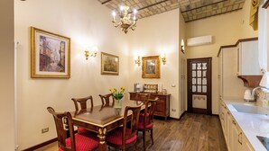 A dining room with a wooden table and chairs, a chandelier, wall-mounted lights, and framed artwork. - Romantic Stay near Santa Maria
Maggiore - Authentic Roman Charm &
Colosseum Walk (Roma)