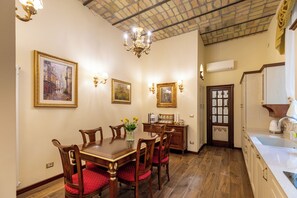 Ein Esszimmer mit Holztisch und -stühlen, einer Chandelüster, Wandleuchten und gerahmten Bildern.