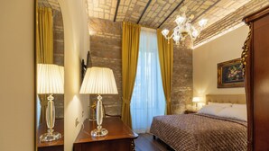 A bedroom with a wooden bed, a nightstand, a mirror, and a chandelier. - Romantic Stay near Santa Maria
Maggiore - Authentic Roman Charm &
Colosseum Walk (Roma)