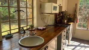 A kitchen with a large window, wooden countertop, and a sink. - Victorian style cottage in Nyanga - 2096 (Nyanga)