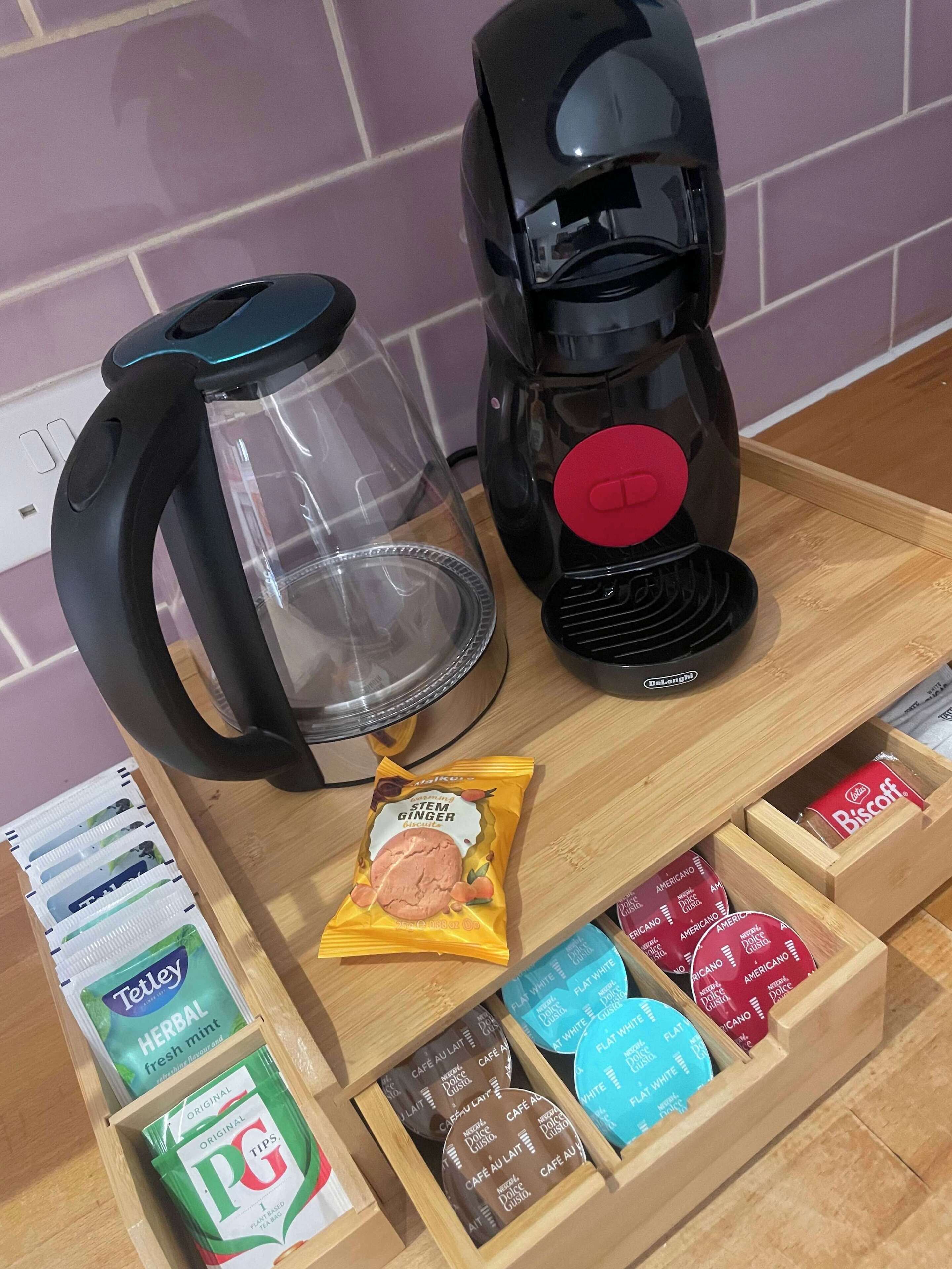 Een koffiezetapparaat, een waterkoker, en een dienblad met theezakjes en biscotti.