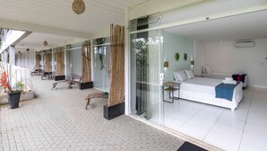 Ein modernes Hotelzimmer mit einem großen Bett, einer Glastür, die auf einen Balkon führt, und einem sauberen, gefliesten Boden.