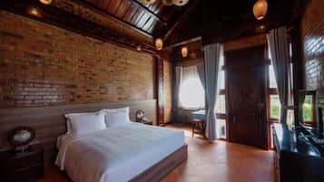 Un dormitorio con pared de ladrillo, cama de madera, mesita de noche y ventana con cortinas.
